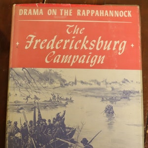 May include: A book cover with a red background and the title "The Fredericksburg Campaign" in white lettering. The cover also features a painting of soldiers crossing a river in boats.