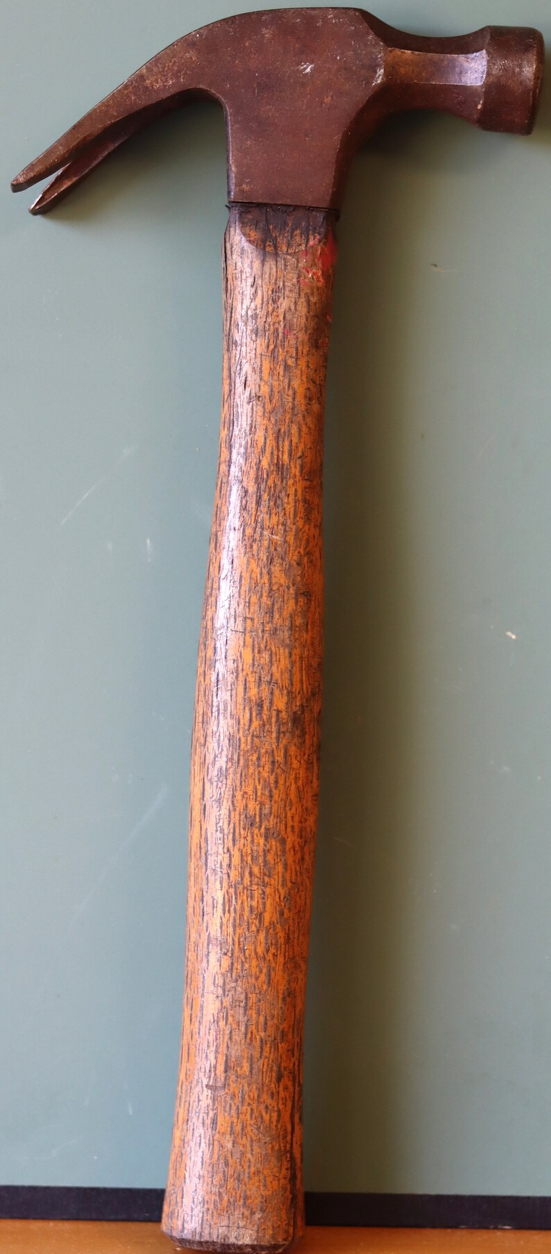 May include: A vintage hammer with a wooden handle and a rusty metal head. The hammer has a worn, weathered look and is a classic tool.
