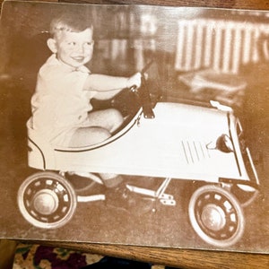 Vintage photo of a child in a toy car