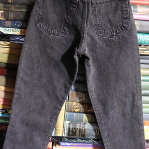 May include: Black denim jeans with a Wrangler label on the back pocket. The jeans have a high waist and a straight leg.