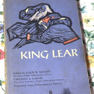 May include: Vintage paperback book titled "King Lear" by Shakespeare. The cover is blue with an illustration of a bearded figure in dark blue robes. The title is in large white letters. The book is a Washington Square Press Book.