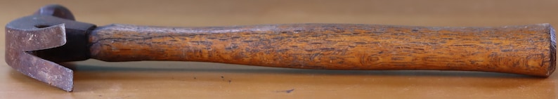 May include: A vintage hammer with a wooden handle. The hammer head is made of metal and has a claw.