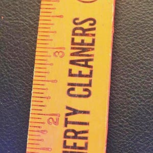 May include: A yellow ruler with red markings and the text "DAUGHERTY CLEANERS (Virgil & Elsie)". The ruler is marked in inches, with visible measurements up to 5 inches.