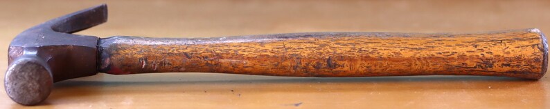 May include: A hammer with a wooden handle and a metal head. The hammer has a brown wooden handle with a textured surface and a black metal head.