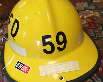 May include: Yellow firefighter helmet with a black number 59 and a 911 Fire, Police, Ambulance sticker.