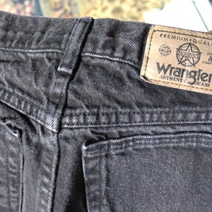 May include: Black denim jeans with a back pocket and a Wrangler label that reads "Premium Quality, Value, Style & Comfort, Wrangler Authentic Jeans".