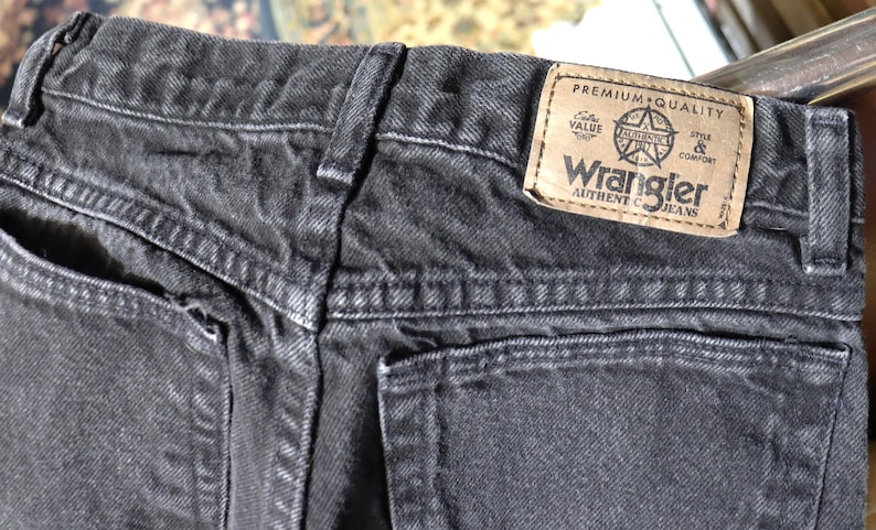 May include: Black denim jeans with a back pocket and a Wrangler label that reads "Premium Quality, Value, Style & Comfort, Wrangler Authentic Jeans".