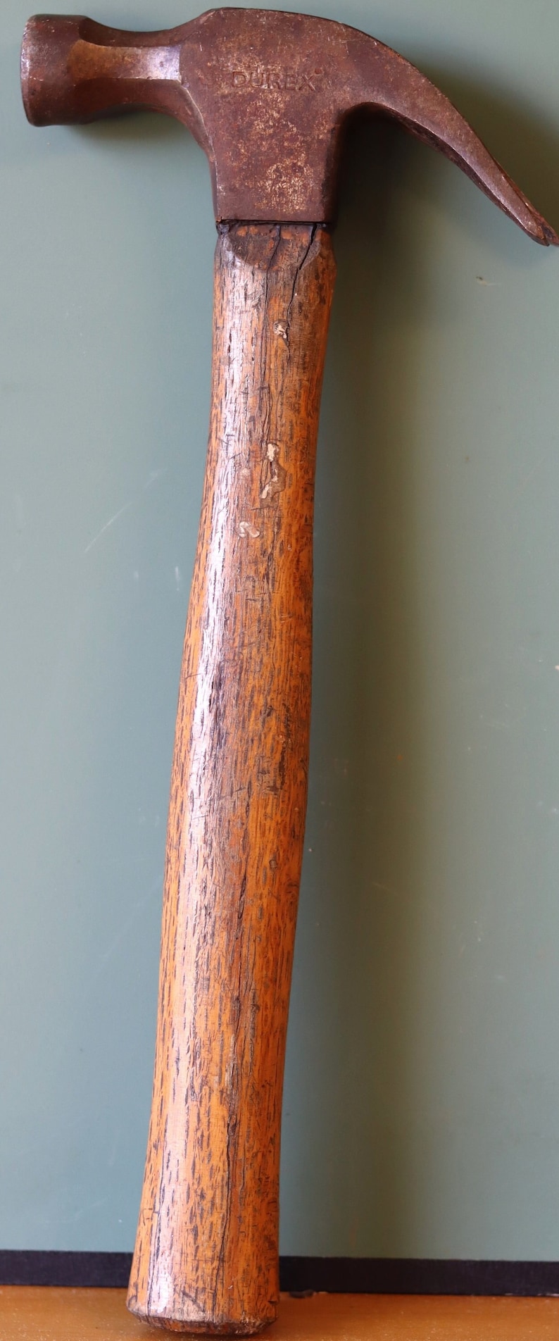 May include: A vintage hammer with a wooden handle and a rusty metal head. The hammer head is stamped with the word "DUREX".