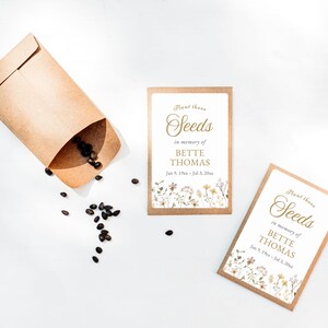 May include: Seed packets with the text "Plant these Seeds in memory of BETTE THOMAS" and floral accents. A kraft paper envelope is open, with seeds spilling out onto a white surface. The dates Jan 9, 19xx - Jul 3, 20xx are also included.