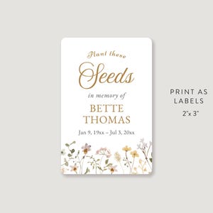 May include: A rectangular label with rounded corners, featuring the text "Plant these Seeds" in gold script. Below, it reads "in memory of BETTE THOMAS" and dates. Floral accents border the bottom. The label is 5.08cm x 7.62cm.