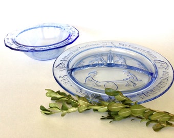 May include: Two blue glass divided plates with a white background. The larger plate has a divided section for food and the words "My First Meal" and "Margery Daw" around the rim. The smaller plate is a bowl with the words "See I Set My Table" and "Where Are You Going?" around the rim.