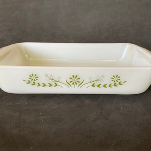 May include: White rectangular baking dish with green floral design. The dish has two handles on the sides.