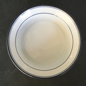May include: A white ceramic bowl with a blue rim and a double blue line around the edge.