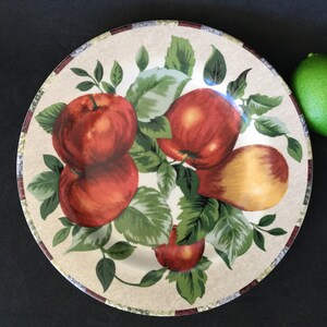 May include: A white ceramic dinner plate with a brown rim and a colorful design of apples and pears on a vine. The plate has a rustic, farmhouse style.
