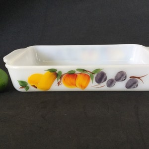 May include: White rectangular baking dish with a painted design of fruit. The design includes pears, peaches, and plums.