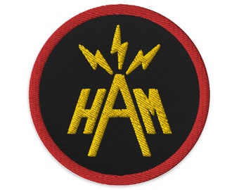 Könnte beinhalten: Ein runder schwarzer und roter Patch mit einem gelben gestickten Design. Das Design zeigt das Wort "HAM" mit Blitzen um den Buchstaben "A".