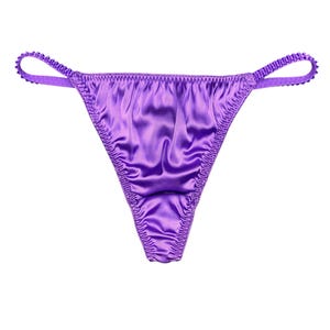 May include: A pair of purple satin thong underwear. The underwear has a low-rise waist and a thong back. The edges are finished with a delicate, ruffled trim. The fabric has a subtle sheen, and the garment is set against a white background.