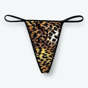 May include: A leopard print thong. The fabric has a pattern of brown, black, and yellow spots. The edges are trimmed with black fabric, and the thin straps are also black.