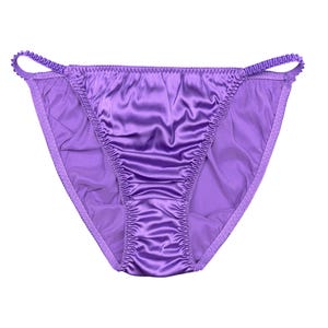 May include: A pair of purple satin underwear with a low-rise design. The underwear has a delicate, ruffled trim along the edges and thin straps. The fabric has a shiny, smooth texture.