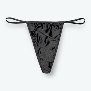 May include: Black thong underwear made of a shiny, ruched fabric. The garment has a triangular front and thin straps that extend to form the waistband. The background is plain white.