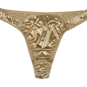 May include: A pair of gold satin underwear with a low-cut back.