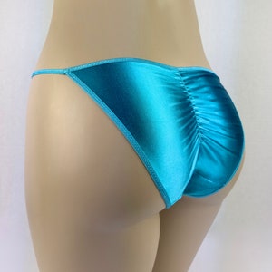 Può includere: Un paio di lingerie in raso blu turchese con la schiena arricciata.