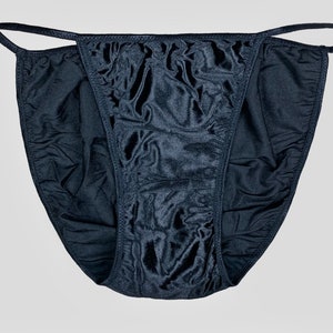 May include: Black satin lingerie with a delicate lace trim. The garment has a low-cut design and adjustable straps.