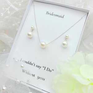 Puede incluir: Una caja blanca con un collar y pendientes de perlas. La caja tiene la palabra "Bridesmaid" impresa en la parte superior y el texto "I couldn't say "I Do" Without you" impreso en la parte inferior.