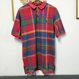 May include: A red, blue, green, and brown plaid polo shirt with a small black polo player logo on the right chest.