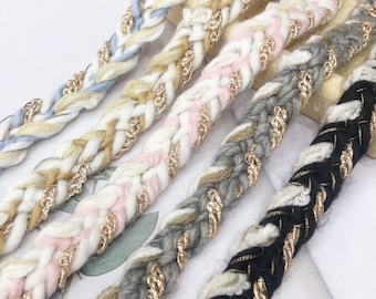 May include: Assortment of braided trim with gold thread accents. The trim is in various colors including black, gray, white, pink, and blue.