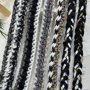 May include: A collection of six black and white trim cords with different textures and patterns. The cords are made of a combination of woven and braided materials.