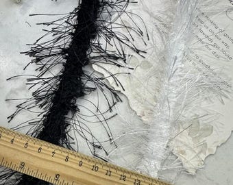May include: Black and white fluffy trim with a ruler for scale. The trim is about 18 inches long.