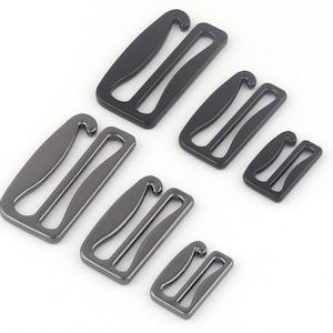 May include: Five metal bra strap extenders in different sizes. The extenders are black and silver in color.
