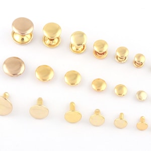 Könnte beinhalten: Sortiment an goldfarbenen Metallnieten in verschiedenen Größen. Die Nieten haben einen runden Kopf und einen Stift zum Befestigen an Stoff oder Leder.