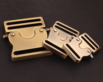 Puede incluir: Tres cierres de hebilla de cinturón de metal dorado antiguo de diferentes tamaños. Las hebillas tienen un acabado liso y cepillado y un diseño simple y funcional.