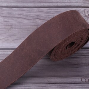 May include: A roll of brown leather strap, perfect for crafting projects. The leather is soft and supple, and the strap is a great choice for making belts, bags, or other leather goods.
