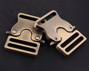 May include: Two antique gold-toned metal clasps with a buckle and two slots. The clasps are connected together.