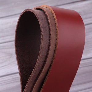 May include: Three leather straps in different shades of brown, rolled up and stacked on top of each other. The top strap is a deep red, the middle strap is a light brown, and the bottom strap is a dark brown.