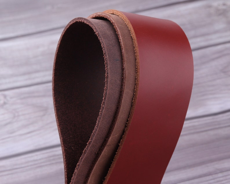 May include: Three leather straps in different shades of brown, rolled up and stacked on top of each other. The top strap is a deep red, the middle strap is a light brown, and the bottom strap is a dark brown.
