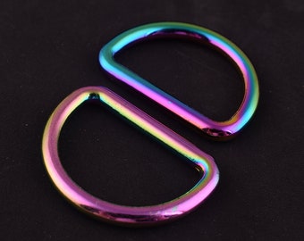 May include: Two iridescent metal D-rings. The rings are a rainbow of colors, including purple, blue, green, and yellow.