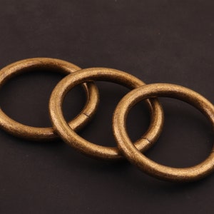 May include: Three interlocking gold-toned metal rings. The rings are smooth and have a polished finish.