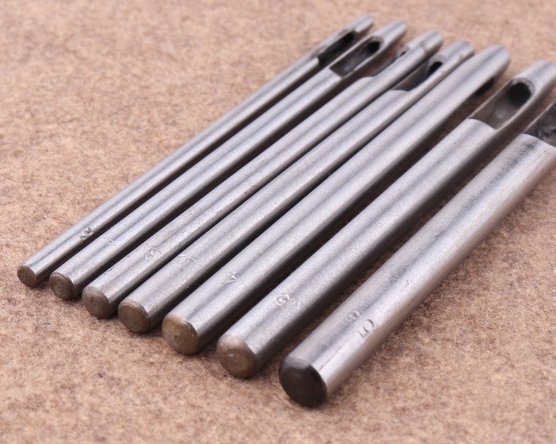 May include: Set of seven silver metal leather hole punches with different sizes, ranging from 2mm to 10mm. Each punch has a handle and a sharp tip.