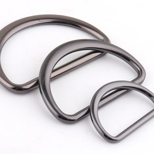 Op de afbeelding: Drie zilverkleurige metalen D-ringen in verschillende maten. De ringen zijn glad en hebben een glanzende afwerking.