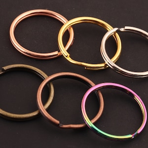 May include: Assortment of five key rings in different colors and finishes, including silver, gold, bronze, and copper.