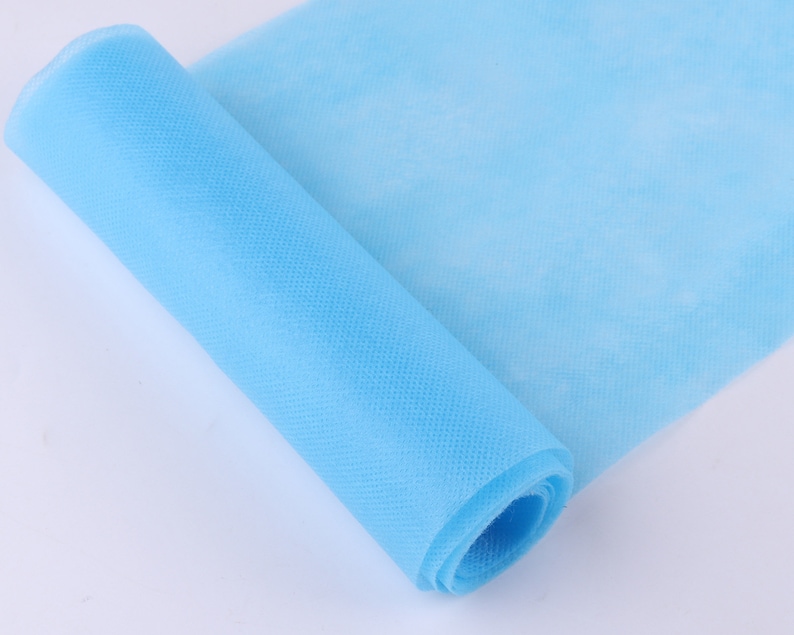 May include: A roll of light blue non-woven fabric. The fabric is rolled up and the end is visible.