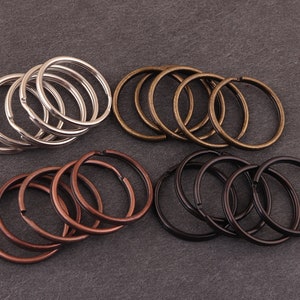 May include: Assortment of key rings in silver, bronze, and black metal. The key rings are stacked and arranged in a circular pattern.