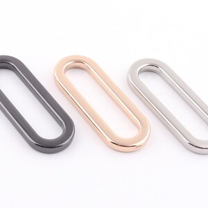 May include: Three oval-shaped metal rings in black, gold, and silver.