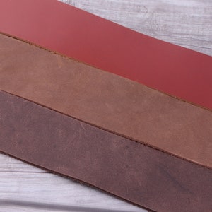 May include: Three strips of leather in different shades of brown and red. The leather is smooth and appears to be high quality.