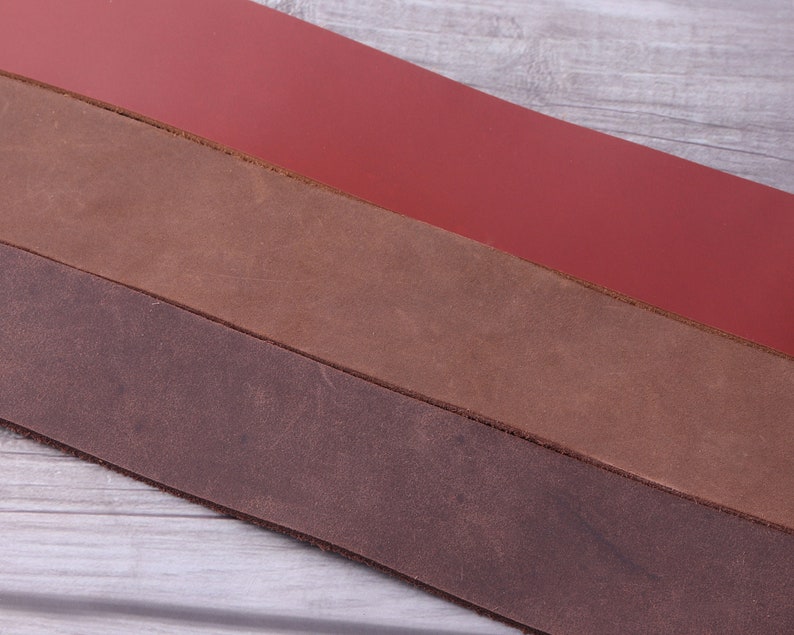 May include: Three strips of leather in different shades of brown and red. The leather is smooth and appears to be high quality.