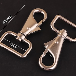 Puede incluir: Dos ganchos de cierre de metal plateado. El gancho más grande mide 63 mm de largo y 25 mm de ancho. El gancho más pequeño es de diseño similar pero más pequeño.